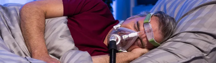 Patient sleeping with a CPAP machine and mask for sleep apnea therapy