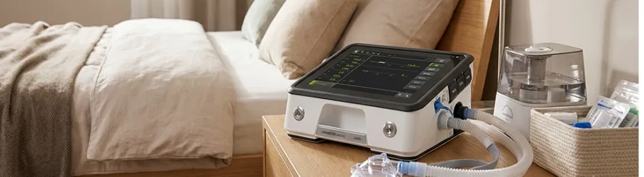 Home ventilator installed on a bedside table with humidifier and breathing circuit ready